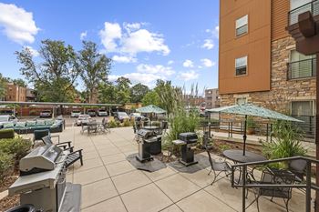 A patio with a grill and chairs.